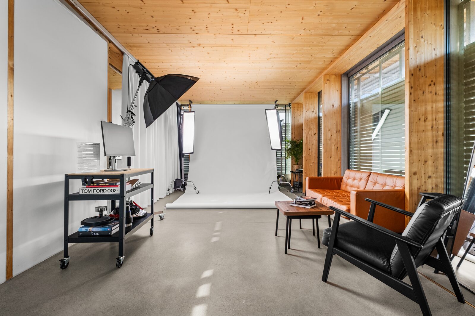 Studio set with a white paper backdrop, lounge corner and daylight windows